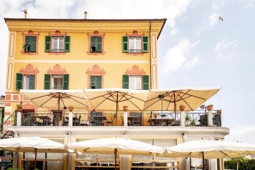 ein Gebäude mit Tischen und Sonnenschirmen davor in der Unterkunft Hotel Miramare in Noli