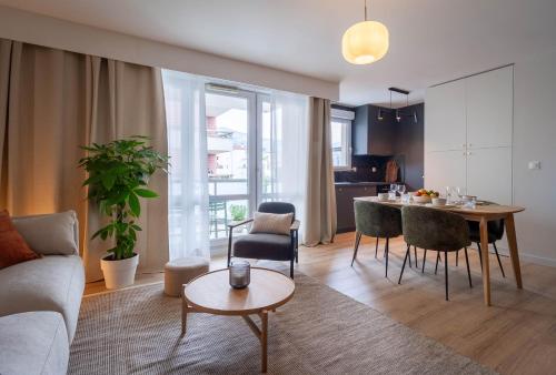 un salon avec un canapé et une table avec des chaises dans l'établissement La Brise 4* I T3 Centre Ville I Garage, à Annecy