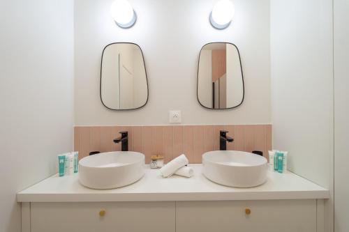 une salle de bain avec deux lavabos et deux miroirs dans l'établissement La Brise 4* I T3 Centre Ville I Garage, à Annecy
