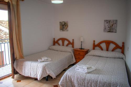 two twin beds in a room with a window at CASA PUERTA ARABE - by Allexperiences in Setenil