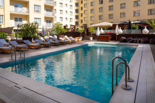 a swimming pool in a hotel with chairs and umbrellas at Wellington Hotel & Spa Madrid in Madrid