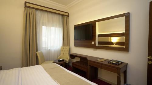 a hotel room with a bed and a desk and a mirror at فندق أفاق المشاعر in Mecca