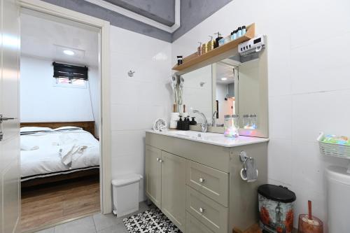 uma casa de banho com um lavatório, um espelho e uma cama em צימר הבקתה em Tiberias