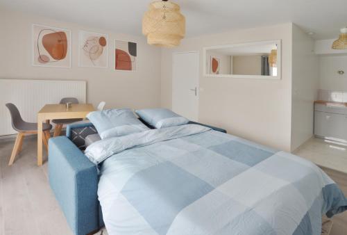 een blauw bed in een witte kamer met een tafel bij La Villa des Arts in Évry-les-Châteaux