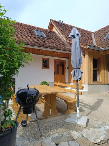 a picnic table and a grill and an umbrella at Ferienhaus Grabenhansl in Stubenberg