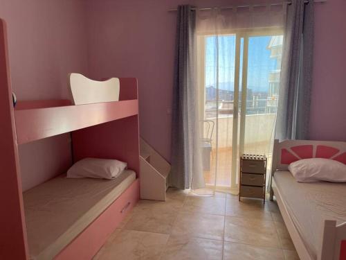 a bedroom with two bunk beds and a balcony at Kea_Apartment_Lushnjë in Lushnjë
