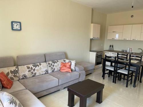 LushnjëにあるKea_Apartment_Lushnjëのリビングルーム(ソファ、テーブル付)、キッチンが備わります。