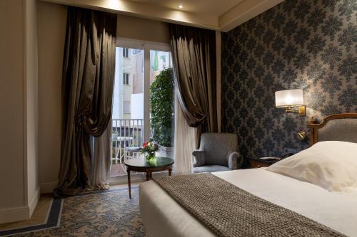 a hotel room with a bed and a chair and a window at Wellington Hotel & Spa Madrid in Madrid