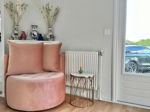 een kamer met een roze stoel en een tafel bij Gezellig en luxe chalet met zicht op het water in Erm