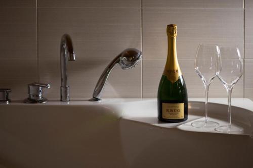 una bottiglia di champagne e due bicchieri di vino su un lavandino di BHL SUITE Jacuzzi LEGNANO a Legnano