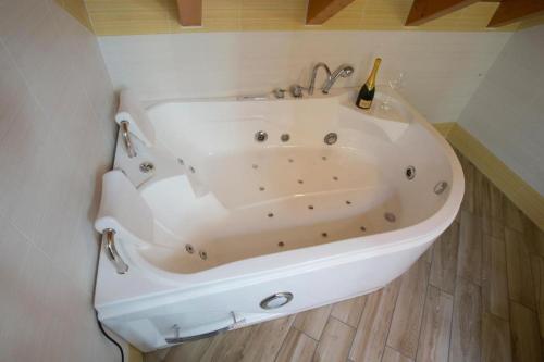 una vasca da bagno bianca con una bottiglia di champagne di BHL SUITE Jacuzzi LEGNANO a Legnano