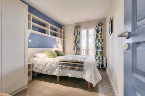 Un dormitorio con una cama y una pared azul. en Residence Lacanau Les Pins - maeva Home, en Lacanau