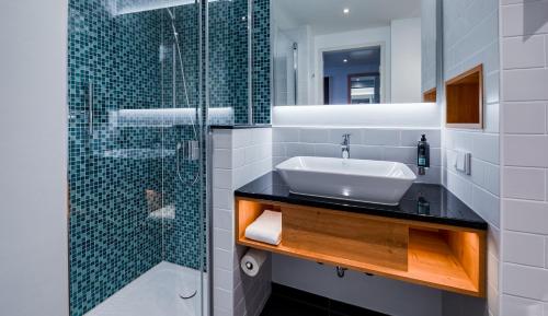 a bathroom with a sink and a glass shower at Premier Inn München Airport Süd in Hallbergmoos