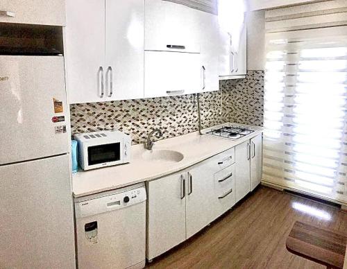 a white kitchen with a sink and a microwave at Halic Apart Hotel in Yalova