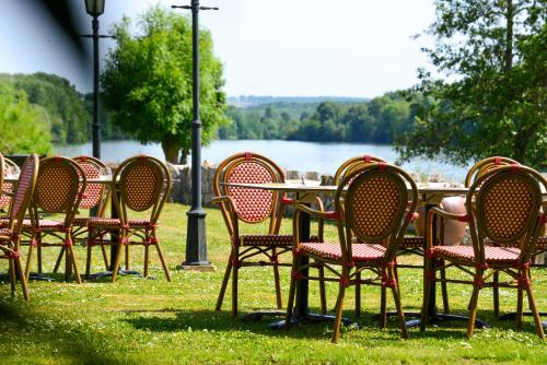 a group of chairs and a table in front of a lake at Hostellerie Saint Pierre in Saint-Pierre-du-Vauvray