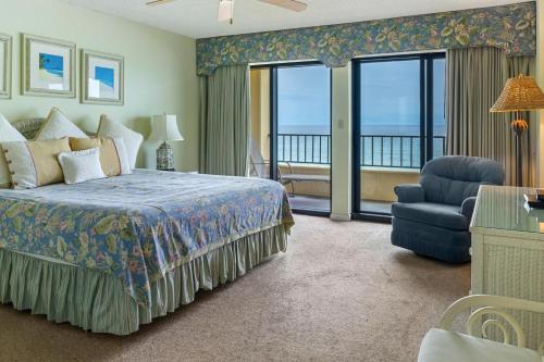 1 dormitorio con 1 cama, 1 silla y balcón en 504 Surf Dweller by Alicia Hollis Realtor Rentals - Open March 16th Week, en Fort Walton Beach