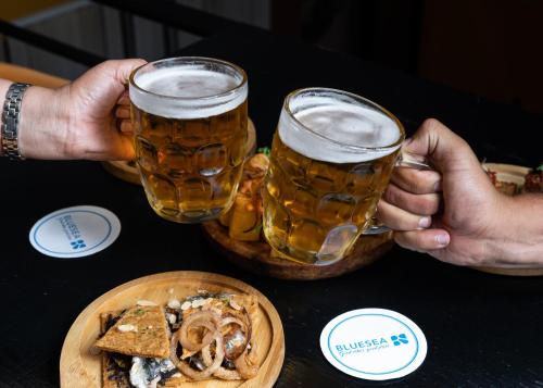 two people holding glasses of beer and a plate of food at Blue Sea Le Printemps in Marrakech