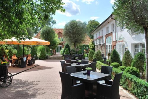 a patio with tables and chairs and people sitting at tables at Van der Valk Golfhotel Serrahn - Adult Only in Serrahn