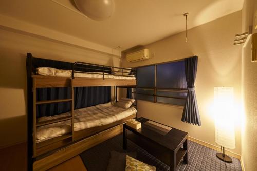a room with two bunk beds and a desk at Oyado Kinokuniya Daikokumachi in Nagasaki