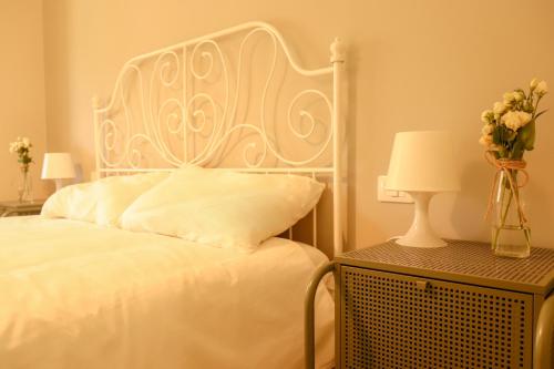 a bedroom with a white bed and a table with a vase of flowers at Azienda Agricola Sebastiani in Cittaducale