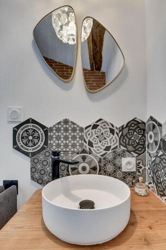 La salle de bains est pourvue de 2 miroirs et d'un lavabo blanc. dans l'établissement Le chant du coquelicot, à Baziège