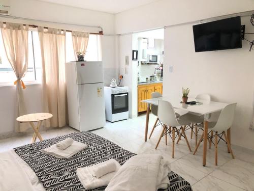 Habitación con cama, mesa y nevera blanca. en Av Corrientes obelisco en Buenos Aires