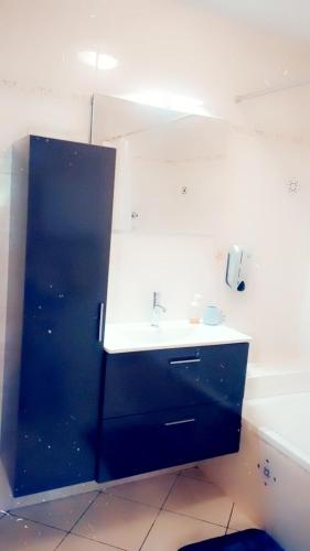 La salle de bains est pourvue d'un lavabo et d'une armoire noire. dans l'établissement Au pied des montagnes., à Saint-Jean-de-Maurienne