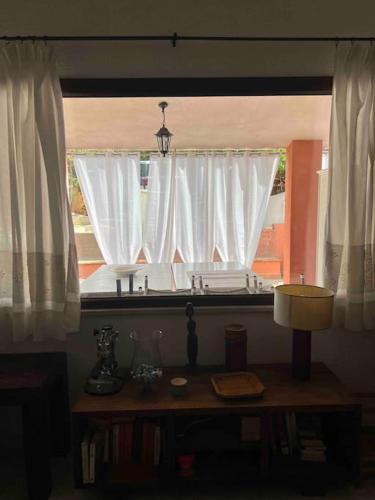 a window with white curtains and a table with a lamp at Vacanze a pochi passi dal mare in Geremèas