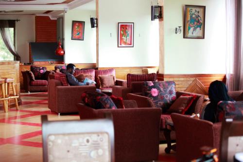 a man sitting on a couch in a waiting room at Bunyonyi Safaris Resort in Kabale
