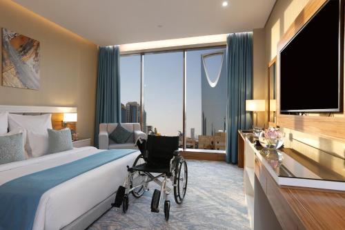 a bedroom with a bed with a wheelchair in front of a window at Cantonal Hotel by Warwick in Riyadh