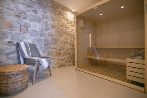 un sauna avec une chaise et un mur en pierre dans l'établissement Villa Bella Vista Heritage Oasis, à Podstrana