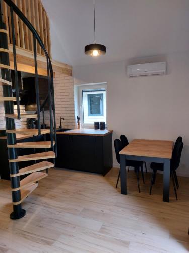 a kitchen and dining room with a table and a spiral staircase at Leśna Osada in Bystrzyca
