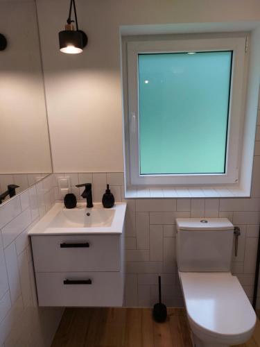 a bathroom with a white toilet and a window at Leśna Osada in Bystrzyca