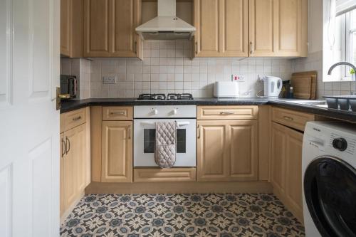 a kitchen with wooden cabinets and a white oven at Maidstone villa 3 bedroom free sports channels,parking in Kent