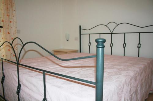 1 dormitorio con cama de metal y sábana blanca en Roccazzurra, en Nova Siri Marina