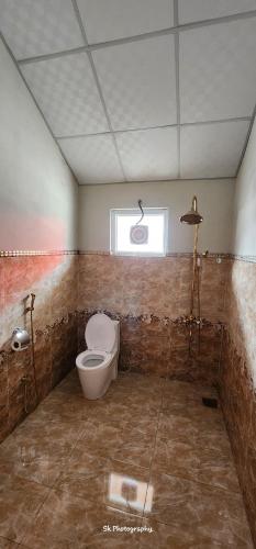 a bathroom with a toilet and a window at Oasis Resort in Skardu