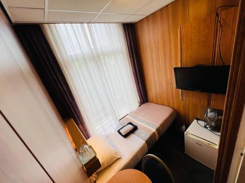 Cama pequeña en habitación pequeña con ventana en Hotel Sharm, en Ámsterdam