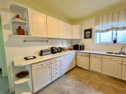 a kitchen with white cabinets and a sink and a window at Ljmonade Hostel in Cascais