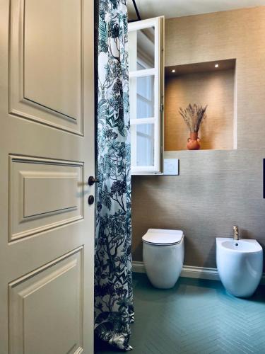 a bathroom with a toilet and a sink and a door at Villa Marengo Guest House in Spinetta Marengo