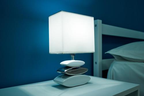 una lámpara sentada en una mesa junto a una cama en La Maison Apparthotel, en Praia a Mare