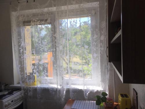 a kitchen with a window with white curtains at Jaukus butas ant Neries skardžio in Vilnius