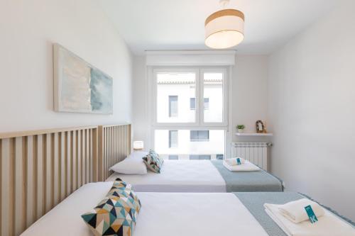 two beds in a white room with a window at Salakobeta - baskeyrentals in Lasarte