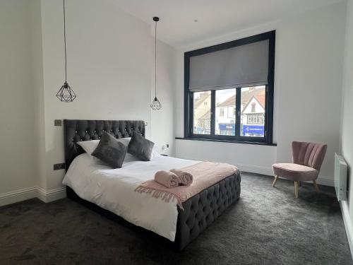 a bedroom with a large bed with a chair and a window at Black Horse Apartments in Knaresborough