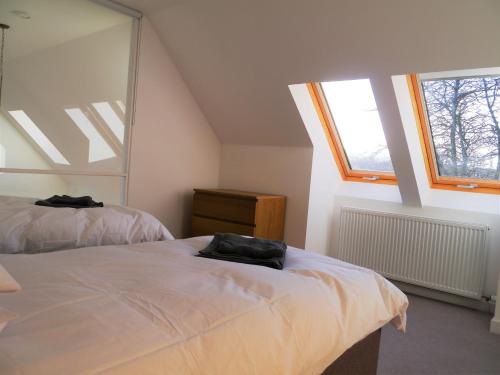 een slaapkamer met twee bedden en twee ramen bij Laundry Cottage in Aberlour