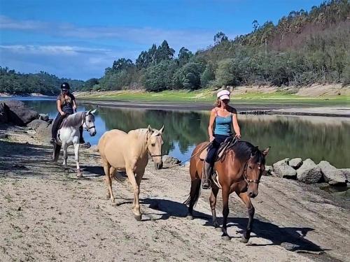 two people riding horses on a beach near a river at Encontro no Rio in Póvoa de Midões