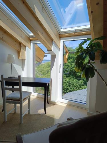 Zimmer mit einem Tisch, einem Stuhl und einem Fenster in der Unterkunft Apartment unterm Dach mit kleinem Seeblick in Münsing