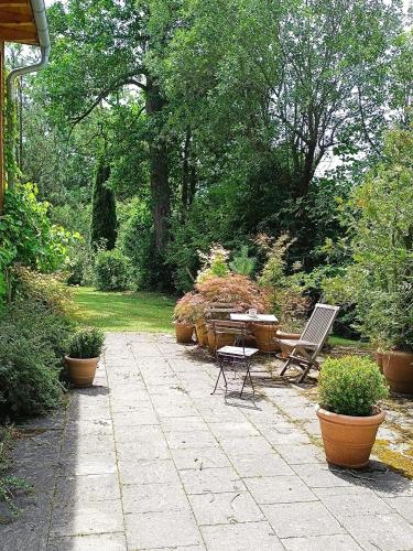 eine Terrasse mit einem Tisch, Stühlen und Topfpflanzen in der Unterkunft Apartment unterm Dach mit kleinem Seeblick in Münsing