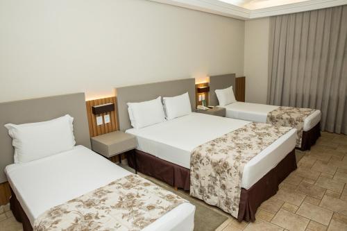 a hotel room with two beds and a room with two tables at Lagos de Jurema Termas Resort in Iretama
