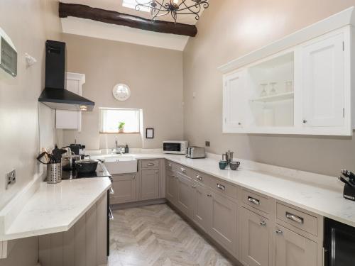 a kitchen with white cabinets and white counter tops at Caton Lane House in Grange Over Sands