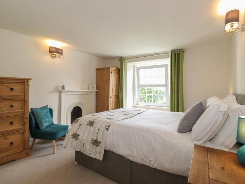 a bedroom with a bed and a window and a chair at Caton Lane House in Grange Over Sands